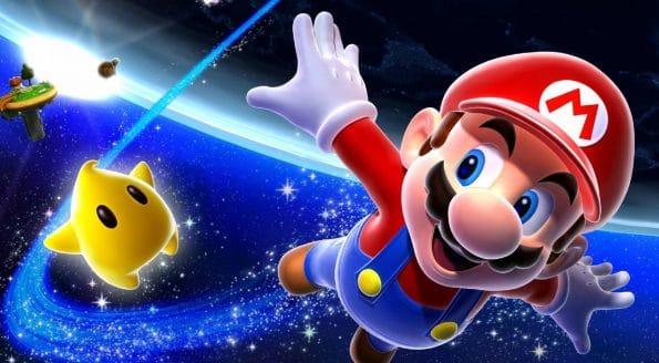 "Vibrant promotional art showing Mario in a dynamic pose, soaring through space towards the viewer. He has a look of excitement and determination, his right hand outstretched as if reaching for something just out of frame. Mario is accompanied by a smiling yellow Luma, a star-shaped companion character. The backdrop is a deep blue starry space with a planet and its orbiting moons to the left, all illuminated by a bright cosmic glow." Published on: LadiesGamers.