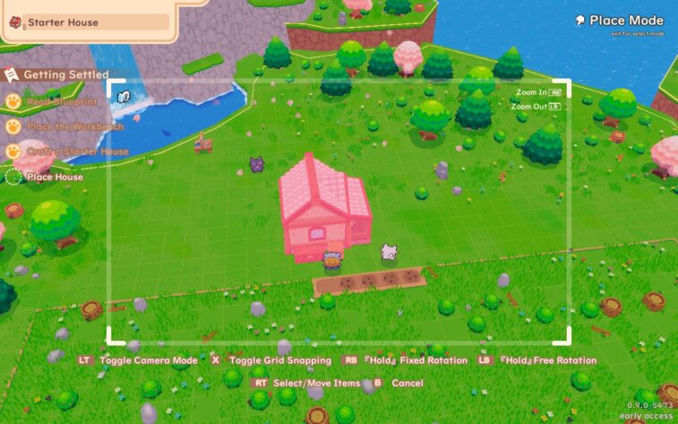 Outdoor customization and camera mode display. A house, in red, is being placed on the farm, between the field and the waterfall pond. A subtle grid is visible across the land to assist in placement, and you can see the options and button prompts to zoom in, zoom out, and toggle various modes for above average levels of customization.