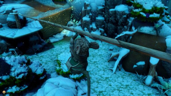A screenshot from a video game showing an anthropomorphic mouse character in a wintery landscape, sliding down a zip wire. The mouse, wearing a green cloak, is crossing a narrow wooden bridge over a snowy chasm. The environment is serene and picturesque, with snow-covered bushes, rocks, and trees, and a magical ambiance created by floating golden particles in the air. The mouse appears focused on its path, embodying a sense of determination and adventure amidst the tranquil beauty of the winter scene.