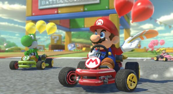 A screenshot from Mario Kart, with Mario in the foreground and Yoshi in the background. Mario is in his red cart and has red balloons tied to it, Yoshi is in a green cart with yellow balloons tied to it. Published on LadiesGamers.com