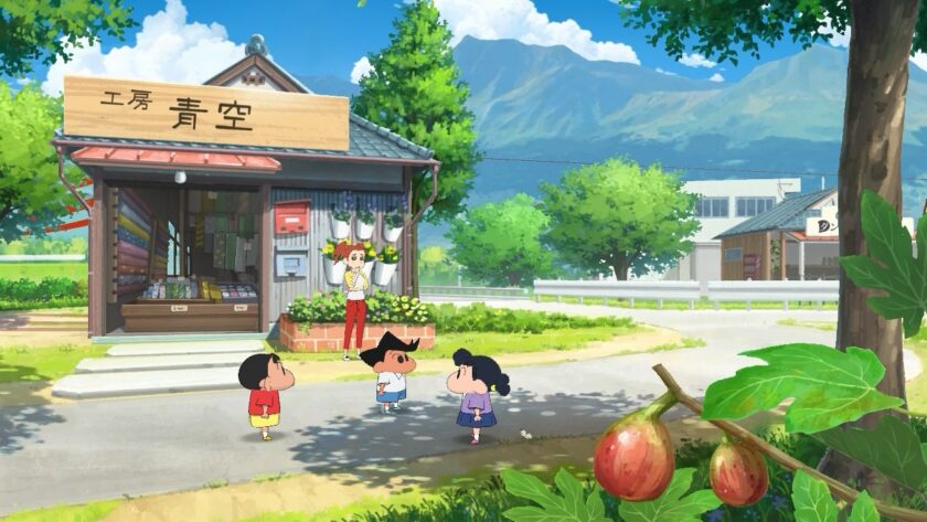 Shin-chan stands with friends in front of a small shop under a clear blue sky. The rustic shop, stocked with colorful goods, has a wooden sign, and lush greenery surrounds the area, with ripe figs hanging from a branch in the foreground. Mountains rise majestically in the background, making the setting feel peaceful and idyllic. Published on: LadiesGamers.