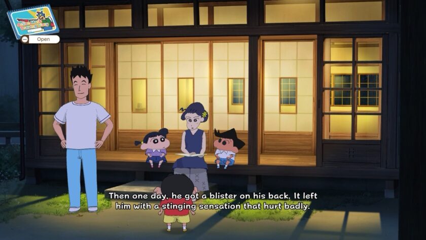 Shin-chan listens intently to a family gathered on the porch of a traditional Japanese home at dusk. The group includes a father, mother, and two children, as they share a story with Shin-chan, highlighted by the text: “Then one day, he got a blister on his back. It left him with a stinging sensation that hurt badly.” The warm, softly lit setting creates a cozy, nostalgic feel. Published on: LadiesGamers.