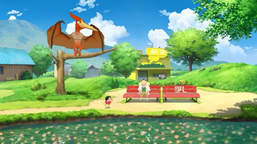 Shin-chan and the professor sit on a red bench by a pond in Shin chan: Me and the Professor on Summer Vacation, under a bright, clear sky. A large, animated pterosaur perches on a tree branch above, giving Shin-chan an amusing companion. In the background, there’s a yellow building labeled “News Paper” and a lovely, rolling landscape. Published on: LadiesGamers.