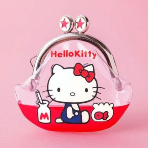 This is a small, transparent coin purse featuring Hello Kitty in a sailor outfit, sitting with a milk bottle and a rice ball. The purse has a metal clasp with two red-starred knobs and a red bottom section. "Hello Kitty" is written in red letters above the character. The background is soft pink, complementing the design's kawaii aesthetic.