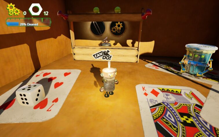 Tiny robot character Buddy stands in a cozy wooden room decorated with oversized playing cards and dice. A booth with gears and a “Can Do!” sign is in the background. Published on: LadiesGamers