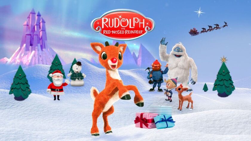 Promotional image for Rudolph the Red-Nosed Reindeer showing Rudolph surrounded by other characters like elves, santa and snowmen. Published on LadiesGamers
