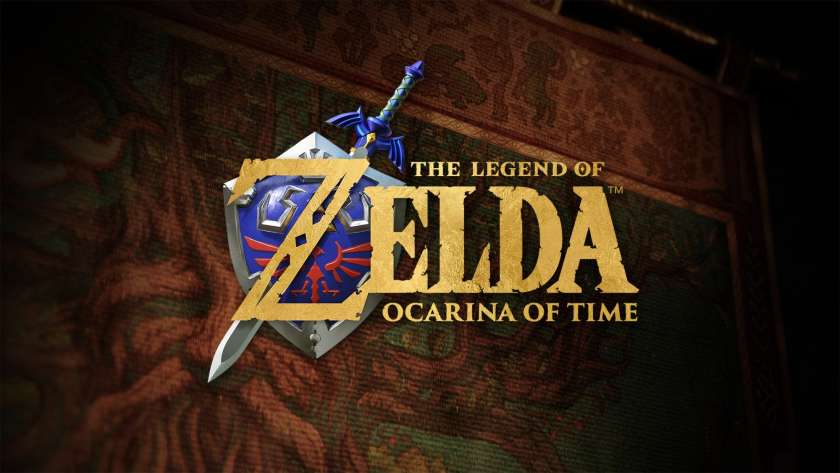 Promotional image for The Legend of Zelda Ocarina of Time, showing the title in gold, with the master sword and shield behind the Z. Published on LadiesGamers